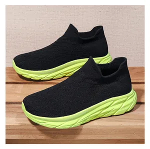 Detail of breathable black knit upper and neon green cushioned thick sole sneakers