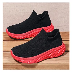 Detail of black knit sock sneakers with chunky red textured soles on wooden surface