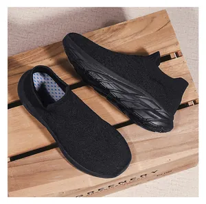 Top down view of black knit slip-on sneakers with breathable mesh on wooden pallet
