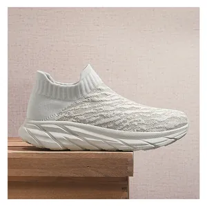 Macro side view of lightweight beige fly-knit slip-on sneakers with thick white soles