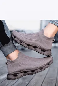Close-up of gray knit slip-on sneakers with wavy hollow cushioning soles on wood