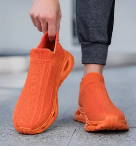 Macro detail of orange knit sock sneakers showing breathable mesh texture and thick hollow sole