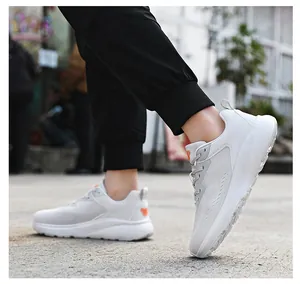 Vue portée de baskets blanches respirantes avec semelle épaisse amortissante et détails orange