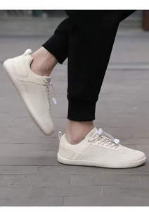 Outdoor shot of beige barefoot sneakers with elastic laces on black pants