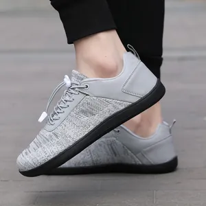 Light grey wide toe barefoot shoes with breathable knit upper and black rubber sole on feet