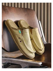 Close-up of khaki canvas backless loafers with frayed edges and white striped sole detail