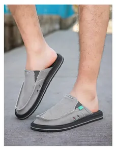 Close-up of grey canvas slip-on mule with frayed edges and dual metal eyelets on thick sole