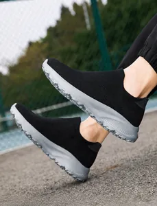 Close-up of black breathable knit slip-on sneakers with grey thick anti-slip sports soles