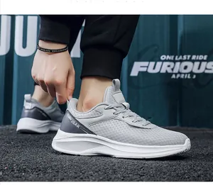 Detailed outdoor shot of light gray breathable mesh sneakers with JGAK logo and white soles