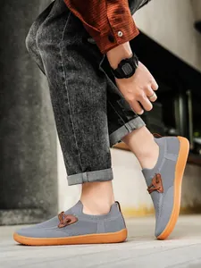 Detail view of breathable grey mesh upper and non-slip orange rubber sole on men's casual shoe