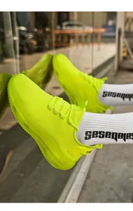 Nahaufnahme neongelber Mesh-Sneaker mit dicker, lichtdurchlässiger Dämpfungssohle