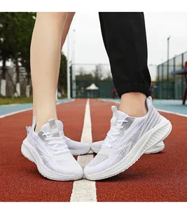 Detail of white breathable mesh running shoes on a red track showing shock-absorbing soles