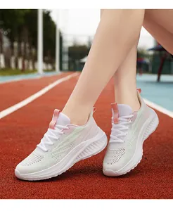 Detailed side view of white mesh running shoes with pink and green gradient stripes on a track