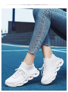 Sneaker in maglia bianca traspirante con suola spessa a onde su pista da corsa all'aperto