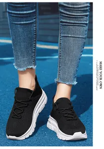 Gros plan de baskets en maille noire avec semelle épaisse blanche sur piste bleue