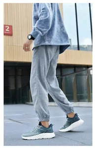 Outdoor-Aufnahme von atmungsaktiven Herren-Laufschuhen mit grauer Jogginghose und Hoodie