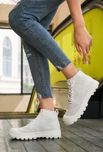 Outdoor shot of cream high-top knitted sneakers with thick non-slip gear soles