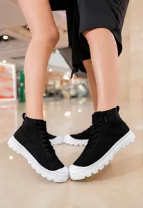 Close-up of breathable black knit high-top sneakers with white lugged chunky soles