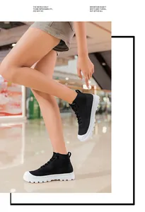 Detail of black breathable knit high-top sneakers with chunky white treaded soles on a model