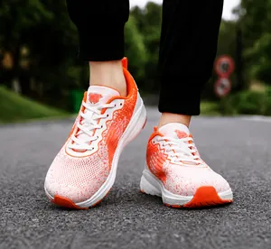 Detail eines atmungsaktiven orange-weißen Mesh-Laufschuhs auf dem Asphalt im Freien