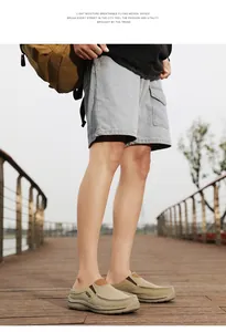 Side view of khaki canvas men's mules on a wooden path showing the stitched details