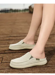 Dettaglio di sabot in tela beige con bordi sfrangiati e nastro verde decorativo