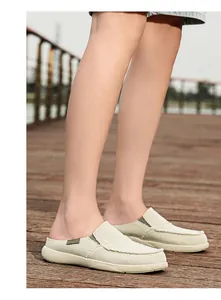 Vista esterna di mocassini sabot in tela beige con dettaglio a nastro verde su legno