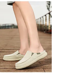 Dettaglio di sabot in tela beige con bordi sfrangiati e suola spessa su pavimento in legno