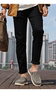 Detail view of men's casual black trousers paired with grey canvas slip-on loafers
