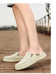 Trama dettagliata delle scarpe sabot in tela beige con finiture verdi su sfondo legno