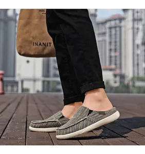 Close-up of grey canvas slip-on mules for men with white stitching and flat rubber soles