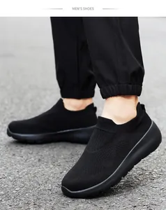 Close-up of black breathable fly-knit men's slip-on sneakers on a pavement road