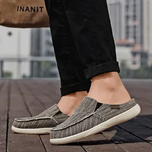 Men's grey canvas mule sneakers with white contrast stitching on outdoor wooden path