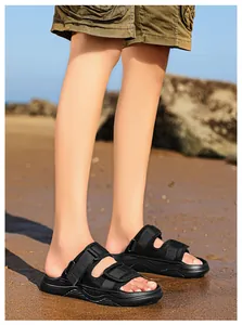 Detail of black beach sandals with adjustable straps on sand showing thick soft sole texture