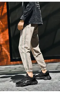 Detail view of khaki joggers with grey side stripes and trendy chunky black sneakers