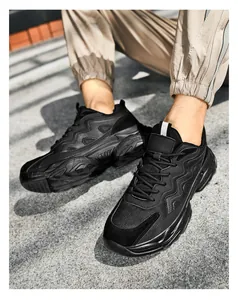 Detail of black chunky dad sneakers with mesh and synthetic leather paneling on street