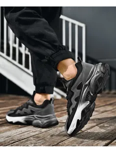 Dynamic low-angle view of men's chunky mesh sneakers with grey and black patchwork design