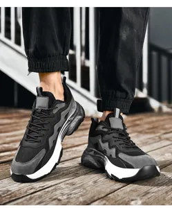 Close-up of black and grey dad sneakers with breathable mesh on outdoor wood floor