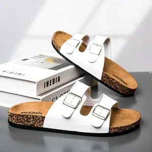 Detail van witte lederen sandalen met dubbele gesp en kurken voetbed en zilveren metaal