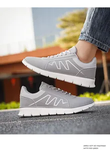Dettaglio delle scarpe sportive grigie da uomo con decoro bianco e suole morbide spesse