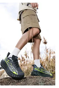 Zwarte hardloopschoenen met neongroene bliksempatronen gedragen in de natuur