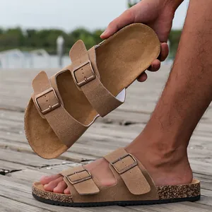 Detail van bruine suède slippers met metalen gespen en een klassieke kurken zool