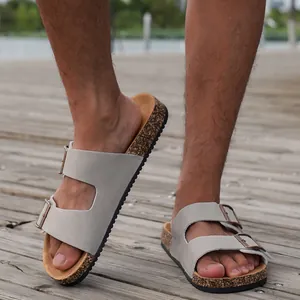 Detailopname van grijze suède sandalen met kurken voetbed op een houten terras buiten