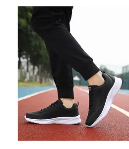 Zwarte heren hardloopschoenen op rode atletiekbaan met witte schokbestendige dikke zolen