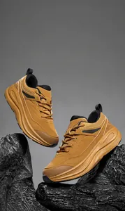 Macro shot of breathable tan hiking shoes on dark rocks showing mesh and sole detail