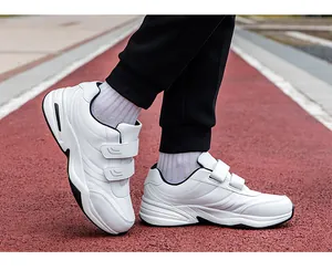 Close-up of white synthetic leather sneakers with double Velcro straps on a running track