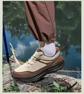 Outdoor shot of men's cushioned hiking shoes in beige and brown leather on lakeside rocks