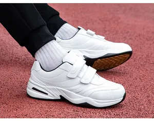 Men's white walking shoes with dual hook-and-loop straps on a red sports track