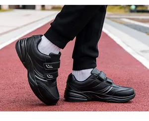 Detail of black walking shoes with dual hook-and-loop straps on a red outdoor track