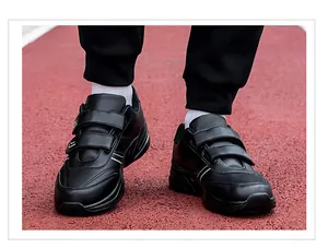 Detail of men's black walking shoes with dual hook-and-loop straps on a red running track